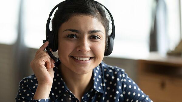 Das Bild zeigt eine junge Frau mit Headset
