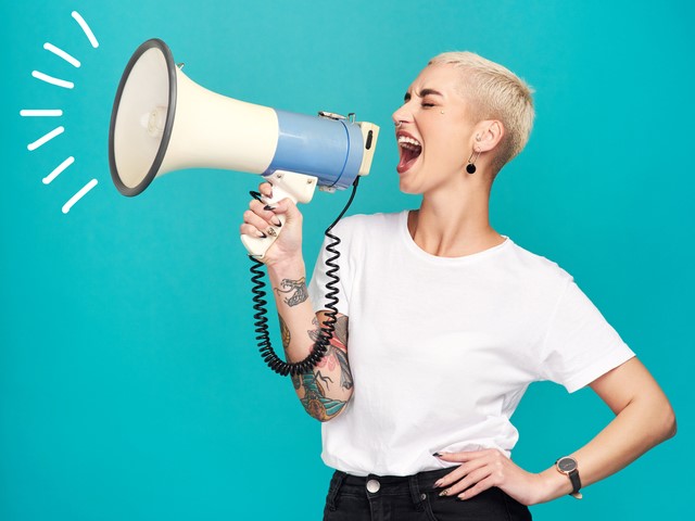 Das Bild zeigt eine blone Frau mit Megaphone
